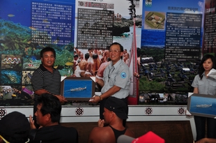 Director Yang of the MNPH presents commemorative photo of dragon boat rowing to one of the warriors, head of township Jian Duo-li