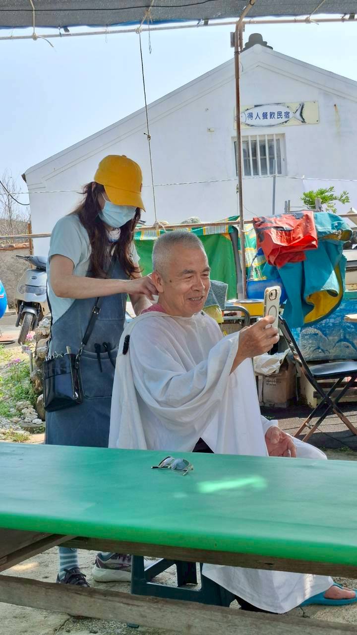 特戰志工徐秀蓉為東吉嶼賣豆花的福春伯義剪,專業的手藝讓福春伯都讚嘆不已。(塗淑卿拍攝)